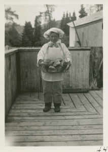 Image of Eskimo [Inuk] boy at school with basket of buns
